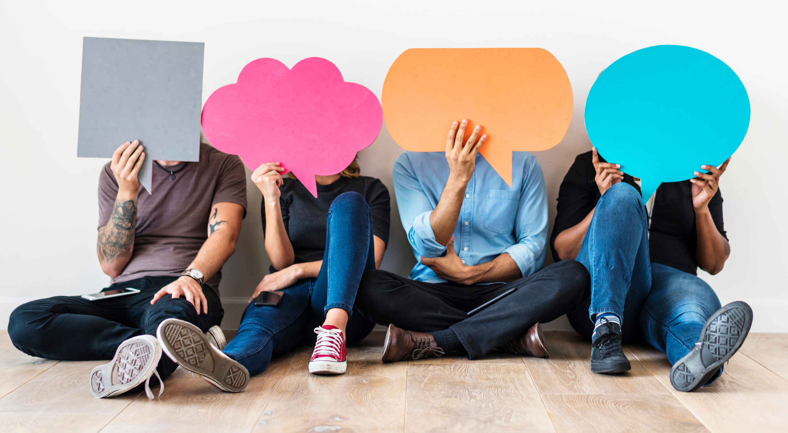 four people holding up differently shaped speech bubbles to show the importance of conversational intelligence